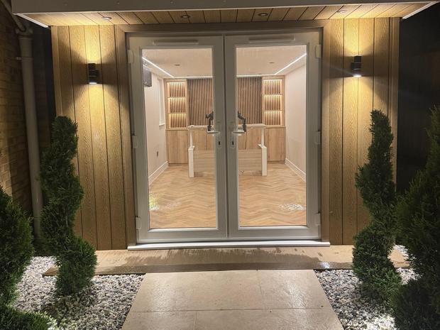 Garden office exterior at night with French doors and a lit approach path